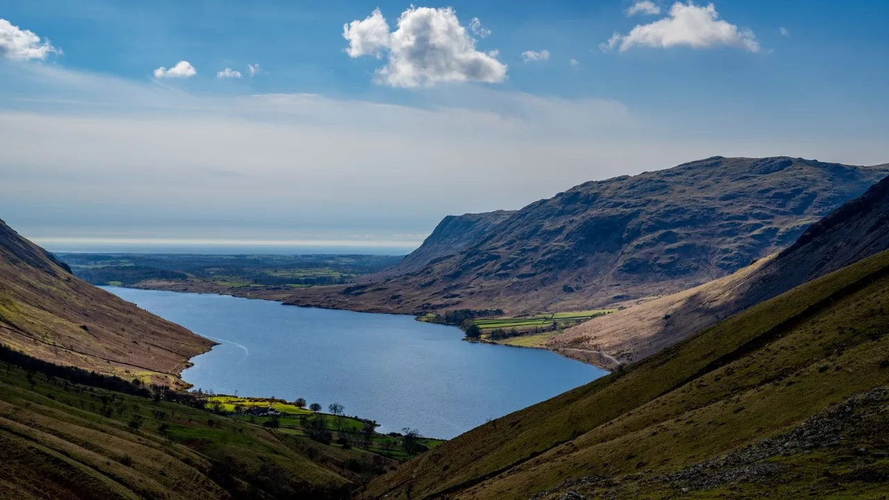 Wast Water stretching between the fells, a Lake District lake ringed by high ground under a bright sky.